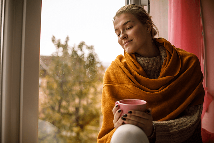 woman next to window in fall with coffee