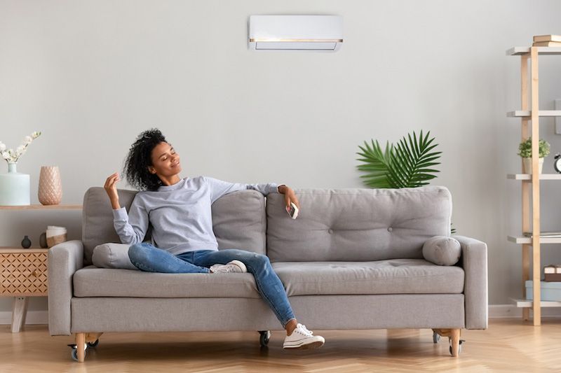 What Indoor Air Quality Accessories Can Help Keep Me Healthy? Image shows woman sitting on couch and looking relaxed.